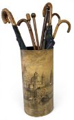 A transfer decorated metal stick stand fitted with a drip tray and a collection of umbrellas and