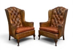 A pair of vintage tan leather upholstered tufted wingback chesterfield armchairs each with a
