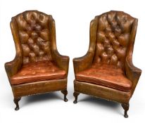 A pair of vintage tan leather upholstered tufted wingback chesterfield armchairs each with a