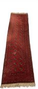 An Afghan style Bokhara runner with two rows of seventeen guls over the burgundy abrash ground