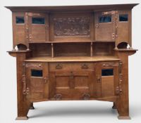 An Arts and Crafts oak sideboard with embossed copper panel and inset coloured glass panes, possibly