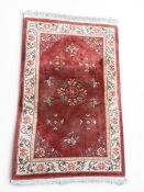 A large Chinese wool carpet with central floral medallion over a burgundy abrash ground within a