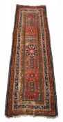 A Caucasian Kazak runner with central flowerhead medallion over an iron red abrash ground within