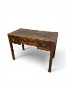 An early 20th century Chinese elm writing desk with a panel top over four frieze drawers raised on
