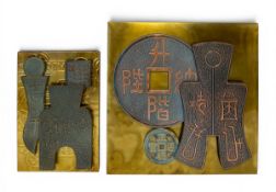 Two contemporary Chinese metal clad wall panels decorated with Feng Shui spade and knife money