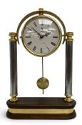 A vintage pendulum mantle clock having a circular brass dial over a pair of chrome columns raised on