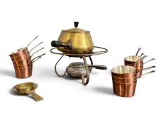 A vintage brass fondue set and burner along with a collection of miniature copper measuring pans.