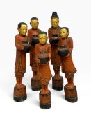 A collection of Burmese carved polychrome standing monks each bearing an alms bowl. H.125 x W.17cm