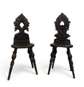 A pair of 19th century north European hall chairs with complementary carved backs above panel
