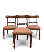 A set of three William IV mahogany dining chairs with carved bar backs above stuffover seats on