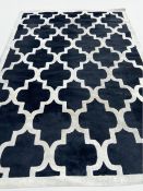 A quatrefoil trellis design carpet with ivory pattern on a black ground. H.200 x W.288cm