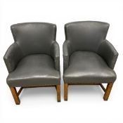 A pair of vintage tub chairs each having a curved back and arms over a cushioned seat upholstered in
