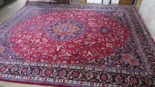 A large Iranian woollen rug, cream, red and blue with fringe size 4.4m x 3.45m