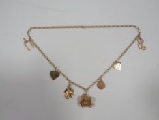 An unusual hallmarked 9 carat gold charm necklace adorned with 7 charms approx weight 26.8g