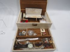 A costume jewellery box and contents to include watches, pendants etc