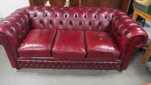 A modern oxblood leather Chesterfield three seater sofa