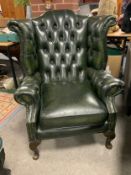 A green wingback leather armchair
