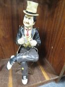 A novelty figure of a man sitting on a metal chair