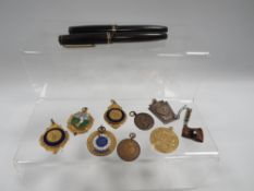 A tub of collectables to include medallions, pens etc