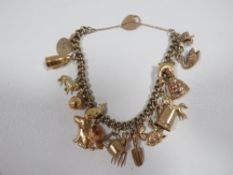 A charm bracelet stamped 9k adorned with approx 17 charms approx weight 28.2g