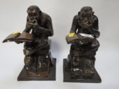 A pair of cast metal figures of a chimp reading a book