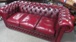 A modern oxblood leather Chesterfield three seater sofa