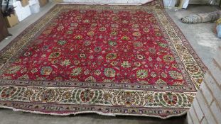 A large Iranian woollen rug, red, green, cream and black floral pattern with fringe Size 4.2m x 3.