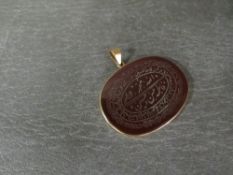 A carved Middle Eastern hard stone panel mounted in unmarked yellow metal