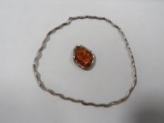 A silver mounted amber pendant together with a silver wavey link necklace