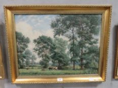 A gilt framed oil on canvas depicting cattle grazing in a woodland meadow with house beyond,