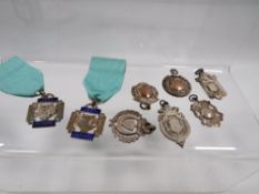 A selection of hallmarked silver watch fobs, medallions etc