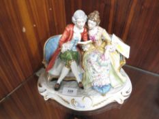 A capodimonte figure of a couple on a chair