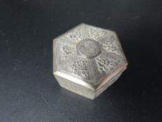 An antique Chinese white metal box of hexagon form with hinged lid, decorated with panels of flowers