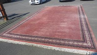 A very large woollen patterned rug with fringe in salmon, cream and blue / black colours 6.4m x 3.8m
