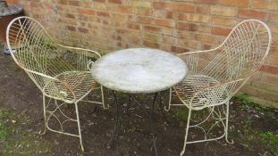 A vintage style wrought iron garden patio set comprising two chairs and a marble topped table