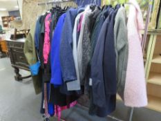 A rail of assorted ladies clothing, comprising jackets, knitwear and dresses etc., to include