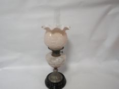 An ornate oil lamp with mottled glass reservoir