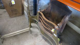 A vintage fire grate with brass front and a fire guard