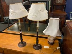 A pair of turned wooden standard lamps together with a modern china example. (3)
