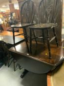 A dark oak dropleaf table and four wheel back chairs (two chairs shown in image)