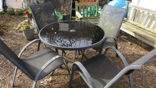 A round glass garden / patio set with table and four stacking chairs