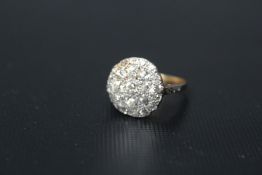 A DIAMOND PAVE RING, having 25 diamonds in graduating circular design, set in unmarked yellow metal,