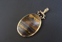 A HALLMARKED 9 CARAT GOLD MOUNTED POLISHED HARDSTONE PENDANT, with contrasting colours on each side,