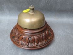 A 19TH CENTURY BRASS COUNTER BELL, on carved wooden base, H 10 cm, Dia 12 cm
