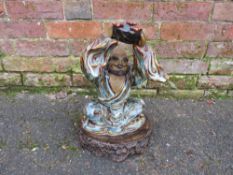 A LARGE TERRACOTTA GLAZED EASTERN MODEL OF A MAN HOLDING A BOWL ALOFT, H 38 cm