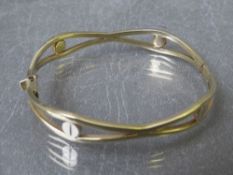 A yellow metal hinged bangle with hallmarks to clasp / end of bangle, approximately 10.03 g