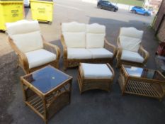 A six piece cane conservatory suite to include two tables, footstool, two seater sofa and two