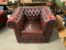 An ox blood red leather chesterfield armchair