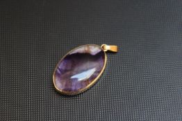 A SMALL HALLMARKED 9 CARAT GOLD MOUNTED OVAL PENDANT, with contrasting colours on each side,