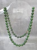 A single strand spinach jade bead necklace, with decorative clasp marked silver to the reverse,
